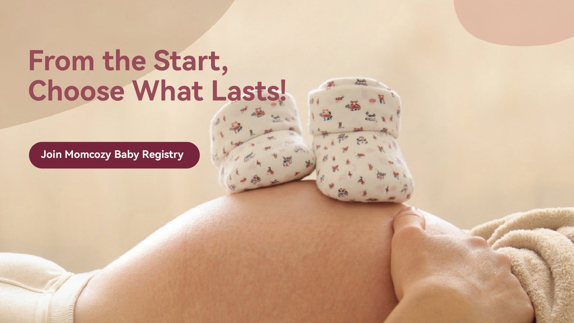 Momcozy baby booties on a pregnant woman's belly